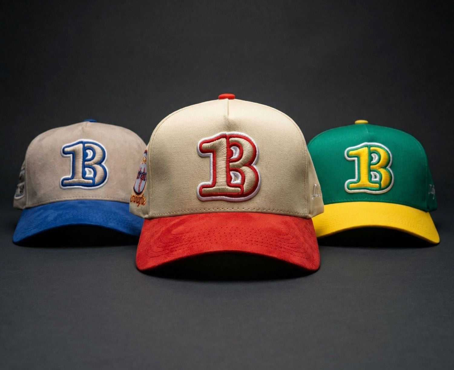 Three baseball caps with different colored 'B' logos on a dark background