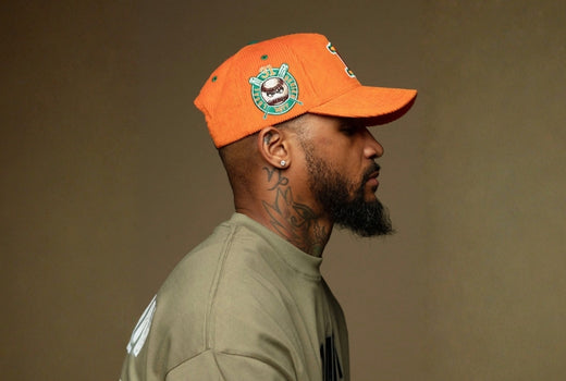 Man wearing an orange cap with a logo on a brown background