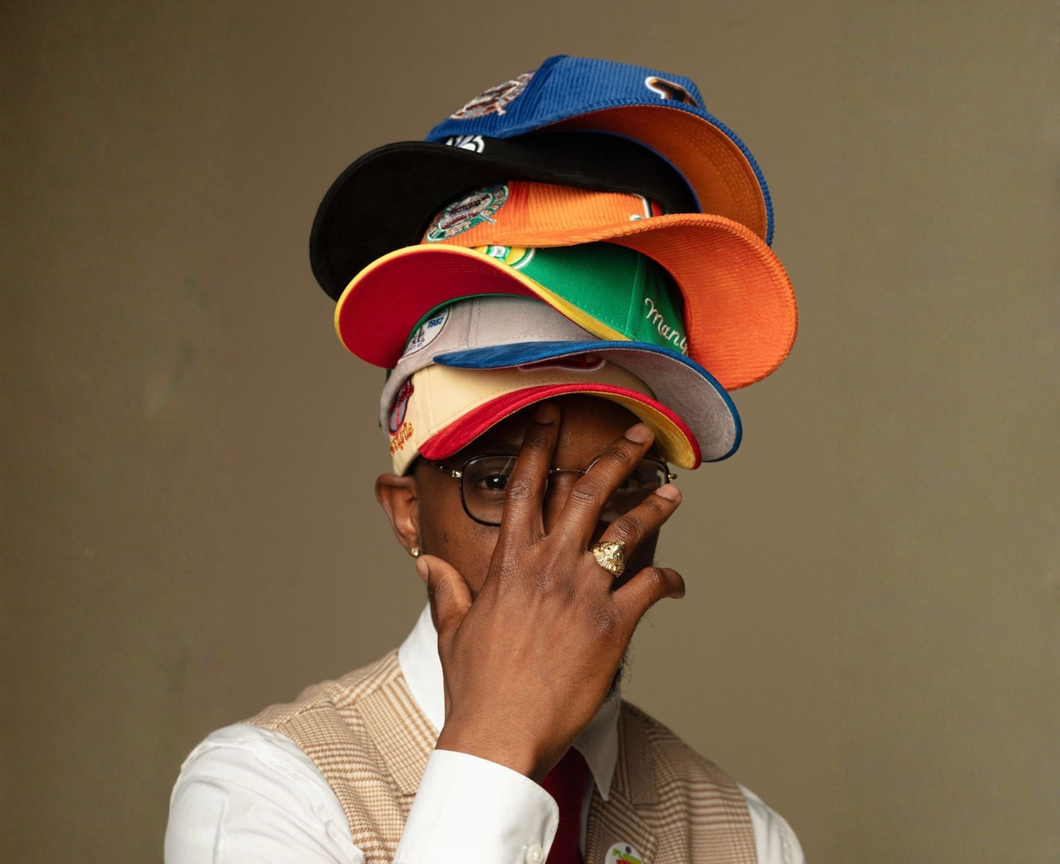 Person wearing multiple colorful caps on a plain background