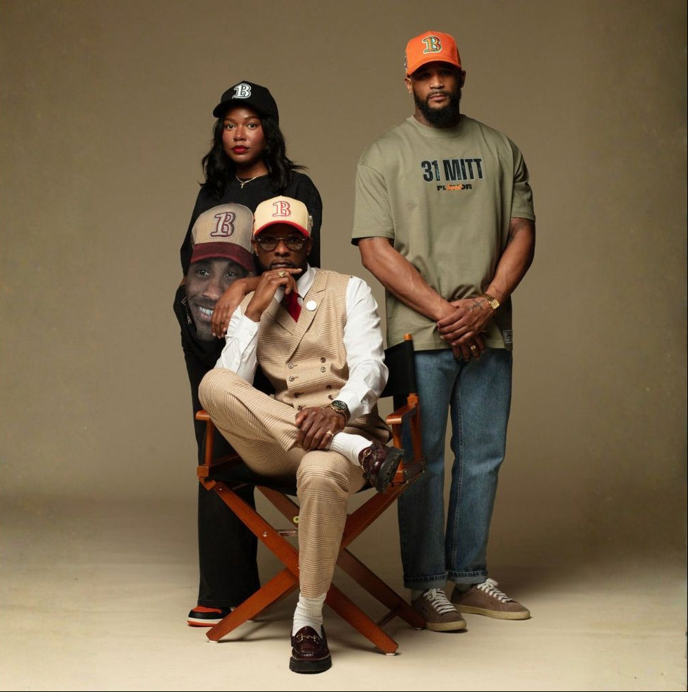 Four people wearing hats and casual clothing against a plain background